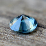 Angled view of the round teal sapphire showing its crown facets