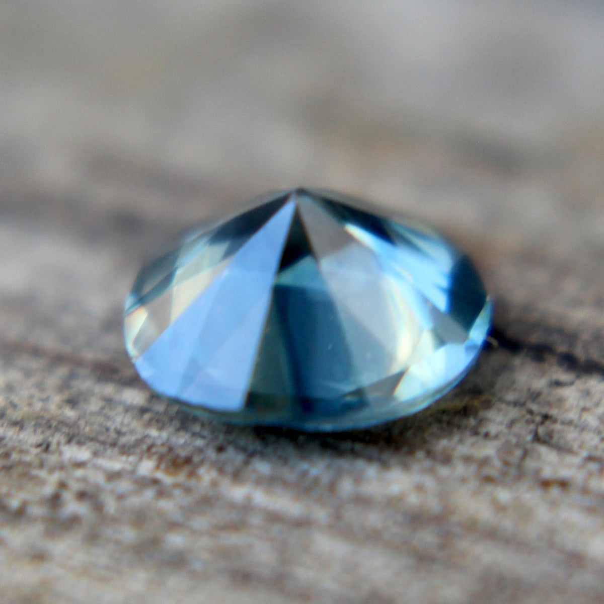 Angled view of the round teal sapphire showing its crown facets