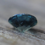 Close-up of the natural teal sapphire showing its blue-green color and facets