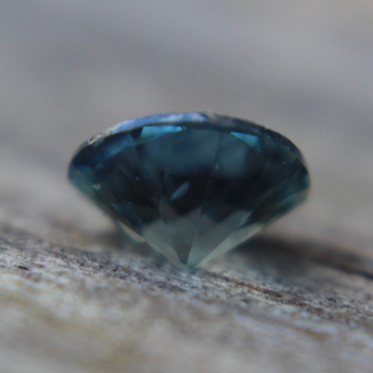 Close-up of the natural teal sapphire showing its blue-green color and facets