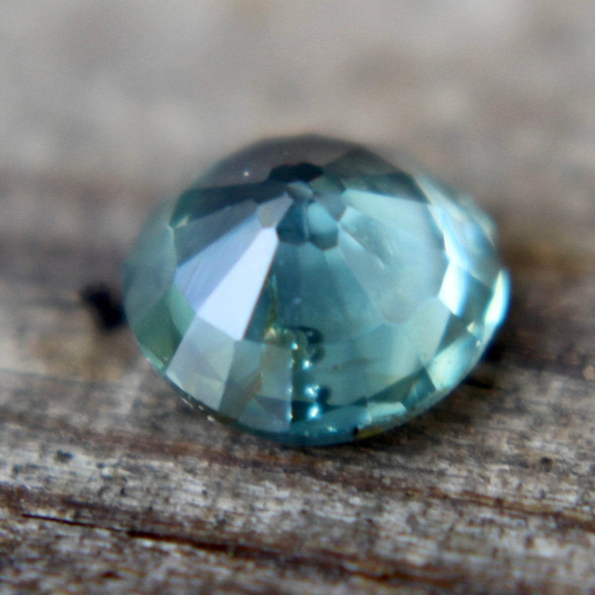 Angled view of the round green sapphire showing its crown facets