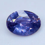 Angled close-up of an oval purple sapphire showing crown facets and visible internal features