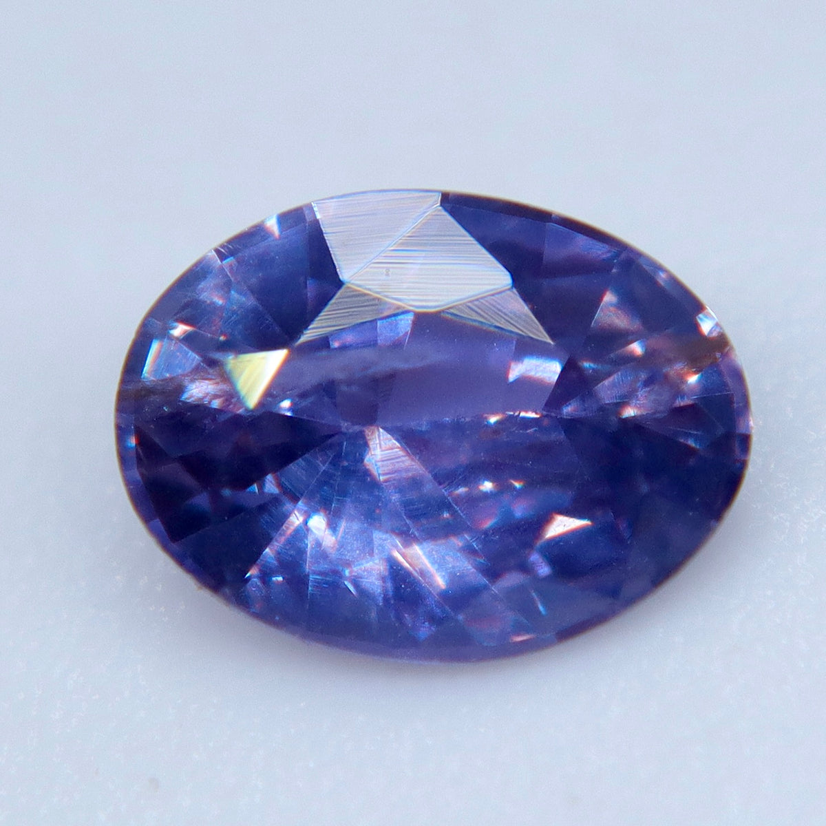 Angled close-up of an oval purple sapphire showing crown facets and visible internal features