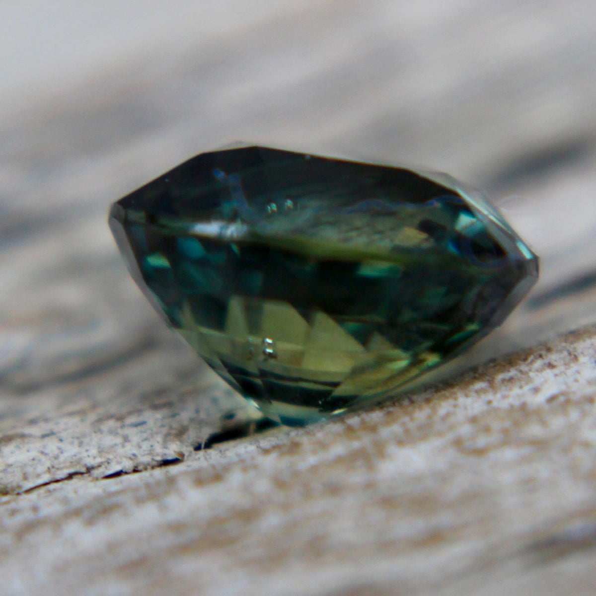 Angled view of a 1.28 carat faceted green sapphire loose gemstone