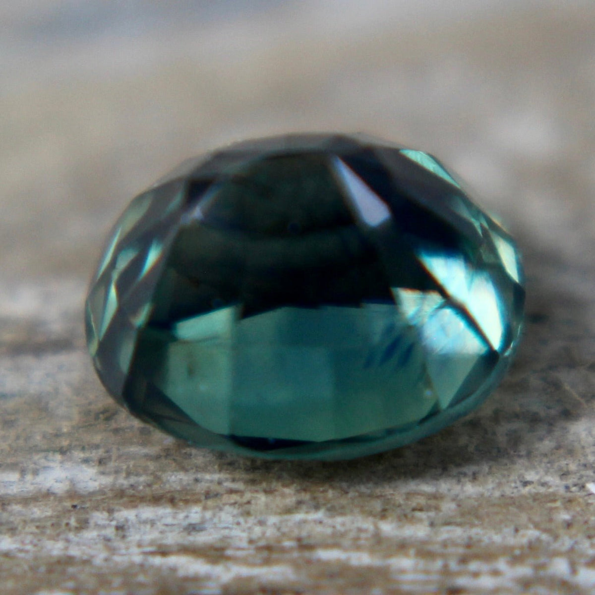 Angled view of a green oval sapphire showing its crown facets.