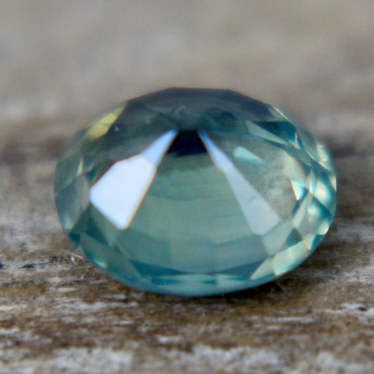 Angled view of a green oval sapphire showing its crown facets.