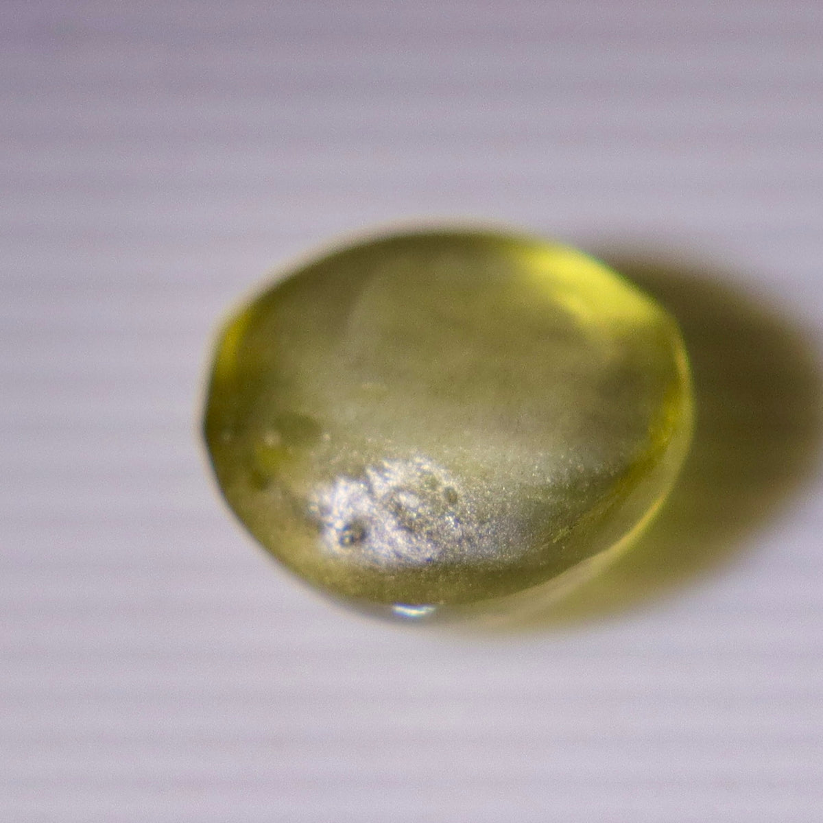 Cat’s-eye cabochon with a golden-brown appearance under warm lighting