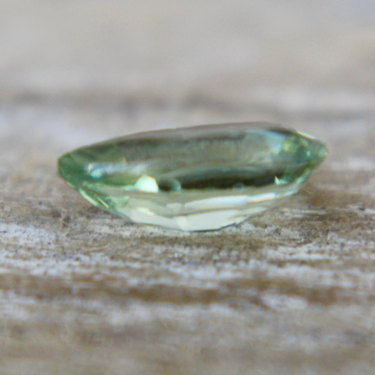 Close-up of the table and surrounding facets of a green pear sapphire.