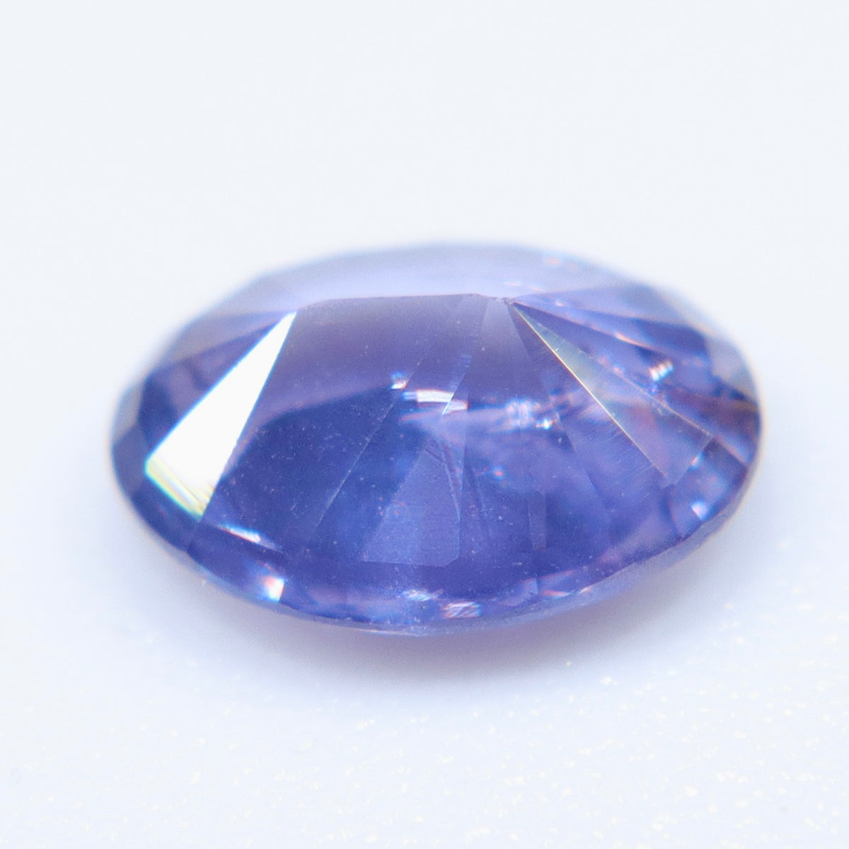 Face-up view of a 0.70 ct purple sapphire showing its oval outline and cool blue undertones