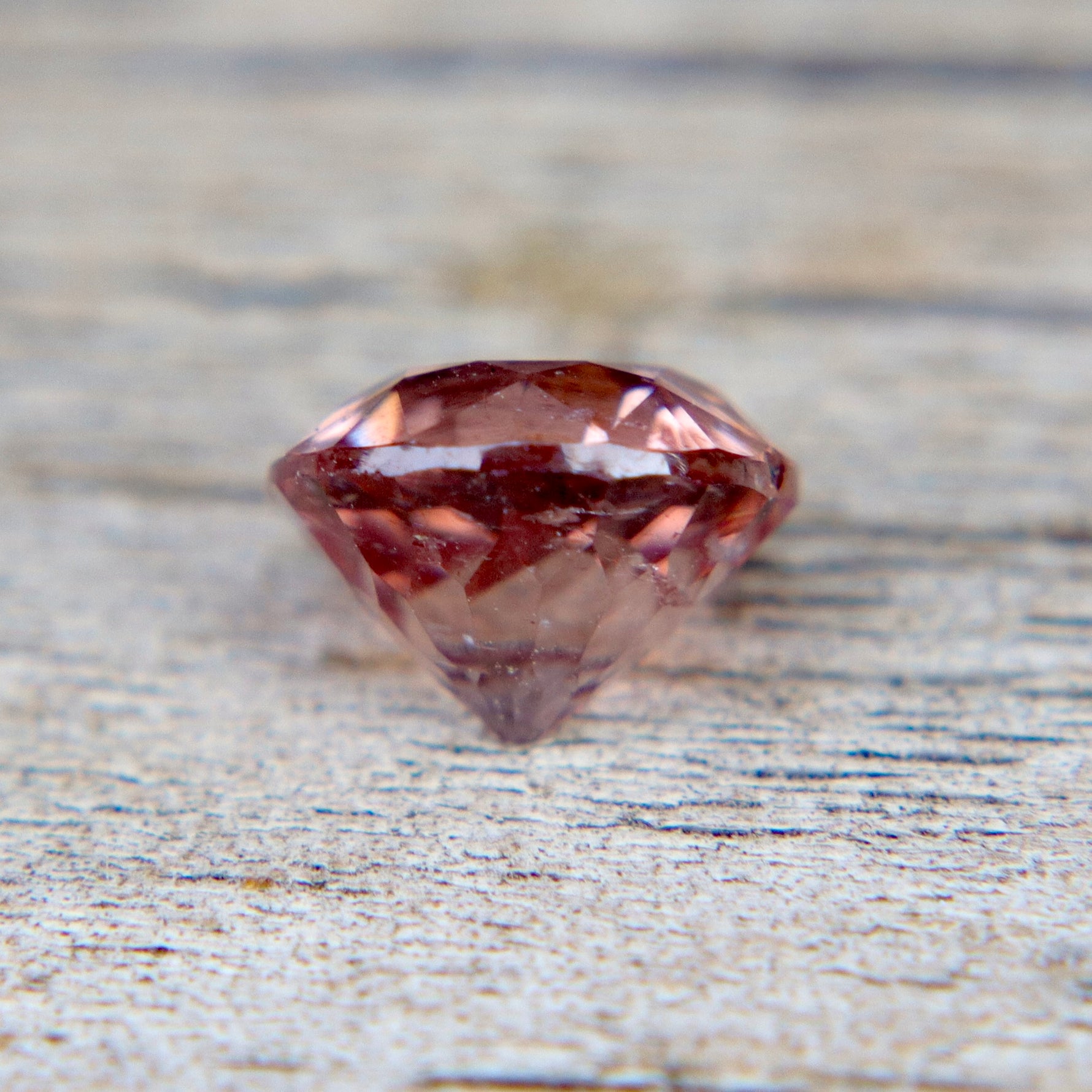 Faceted purple gemstone on a textured surface