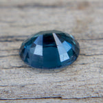 Faceted blue gemstone on a wooden surface