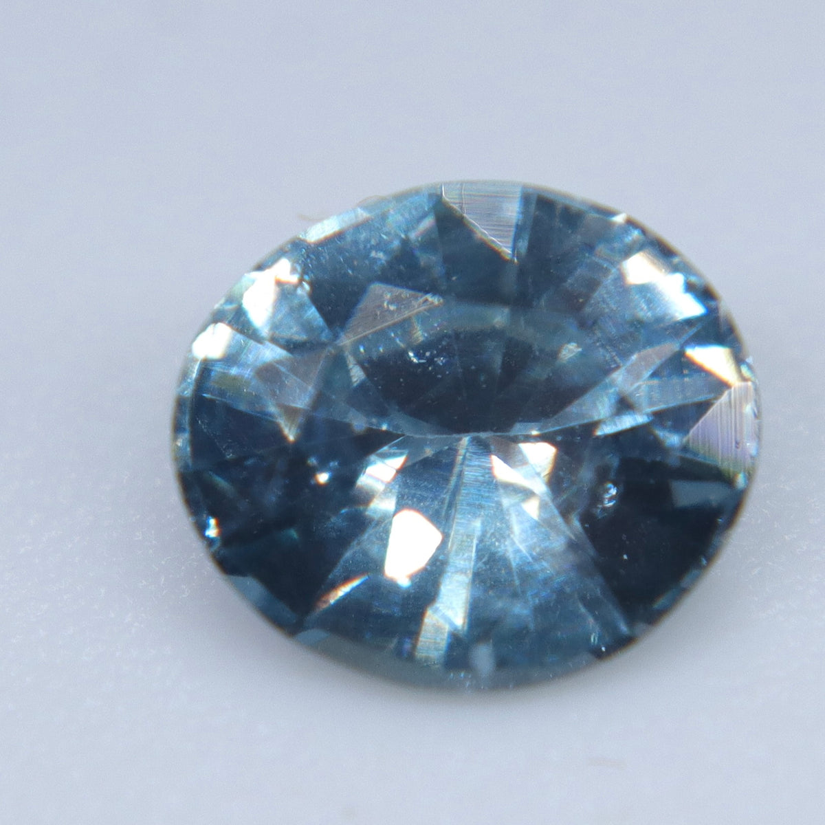 Natural Madagascar teal sapphire in an oval cut, viewed face-up on a light background
