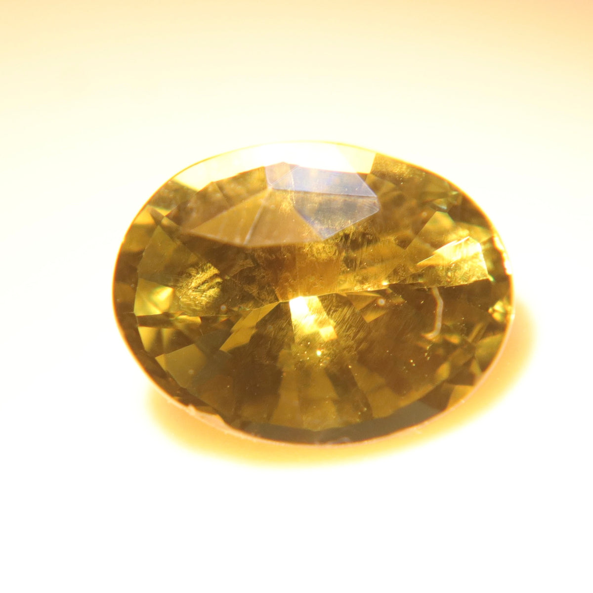 Oval-cut 1.60 ct Ceylon alexandrite showing golden-orange tones under warm lighting.