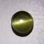 Oval cat’s-eye gemstone photographed under purple lighting