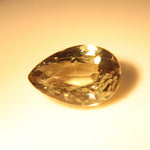 Pear-cut alexandrite showing golden-orange tones under warm lighting.