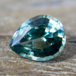 Side profile of a loose green pear-cut sapphire showing its crown and pavilion.