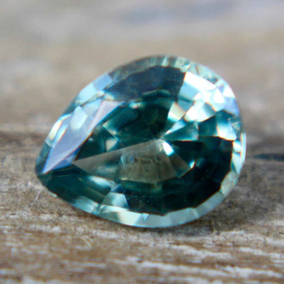 Side profile of a loose green pear-cut sapphire showing its crown and pavilion.