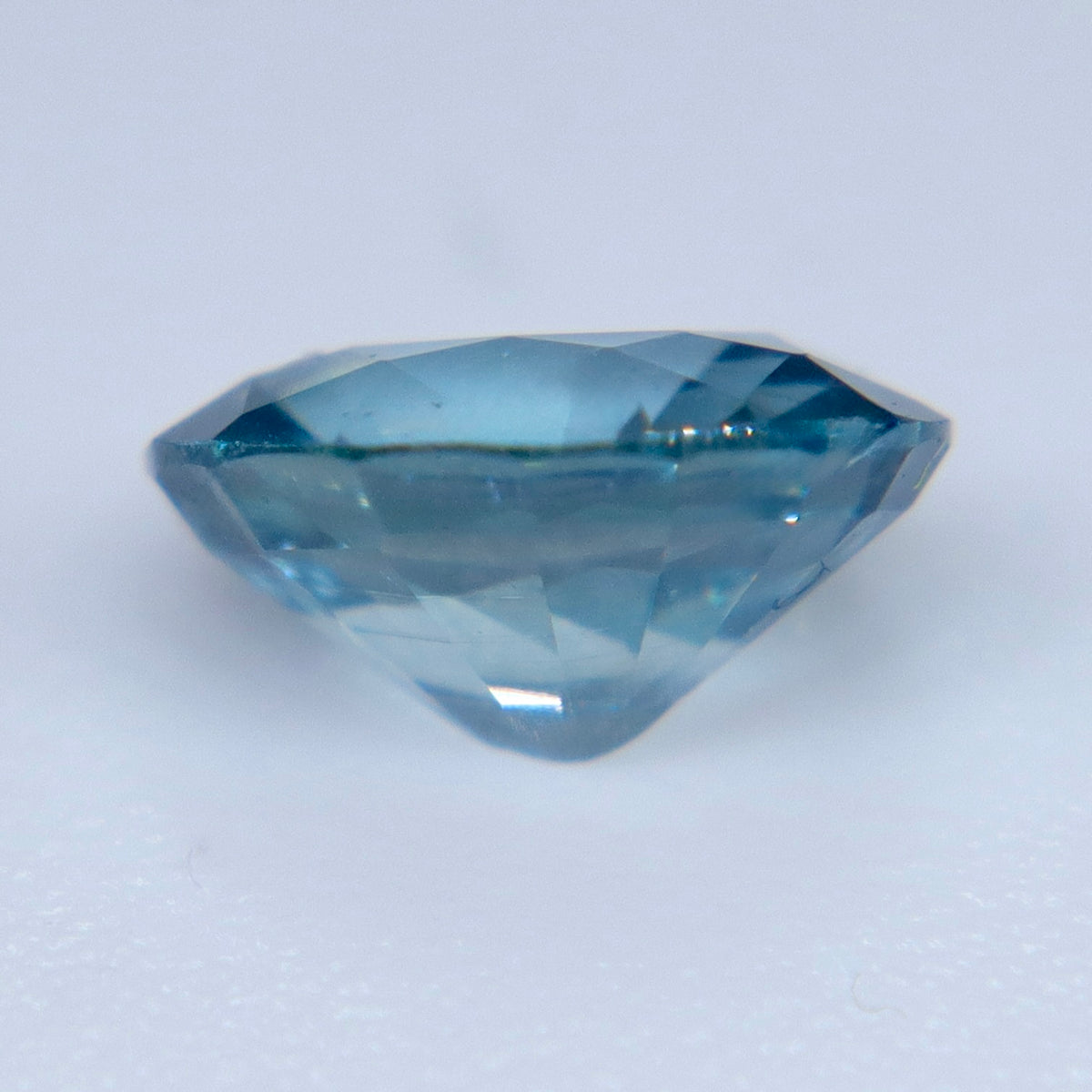 Underside view of a loose teal sapphire showing its polished pavilion facets