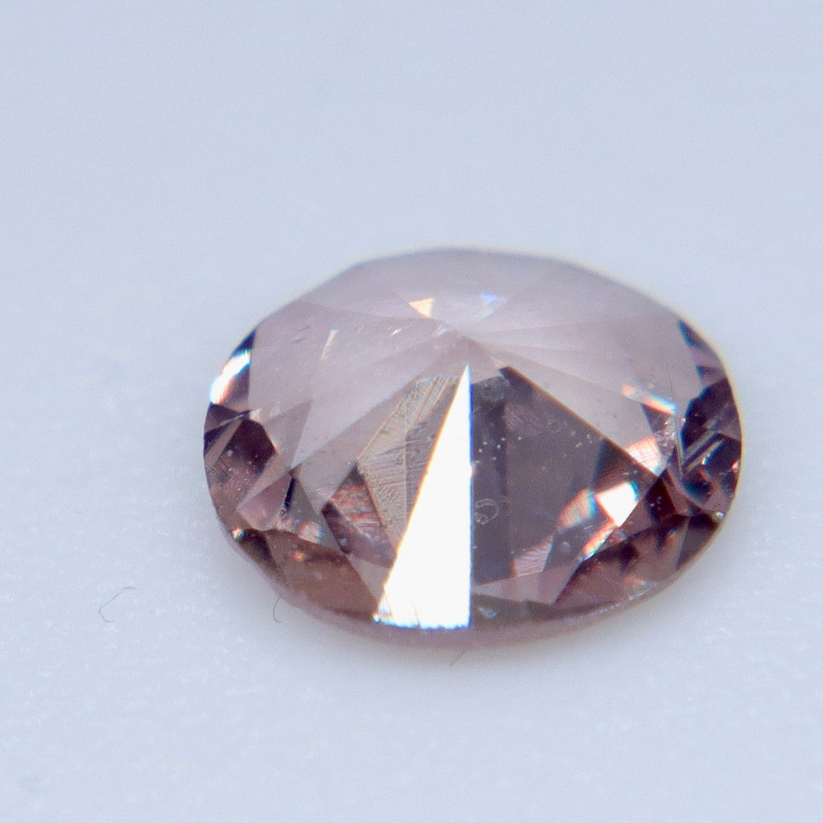 Underside view of a peach-pink sapphire showing its pavilion facets