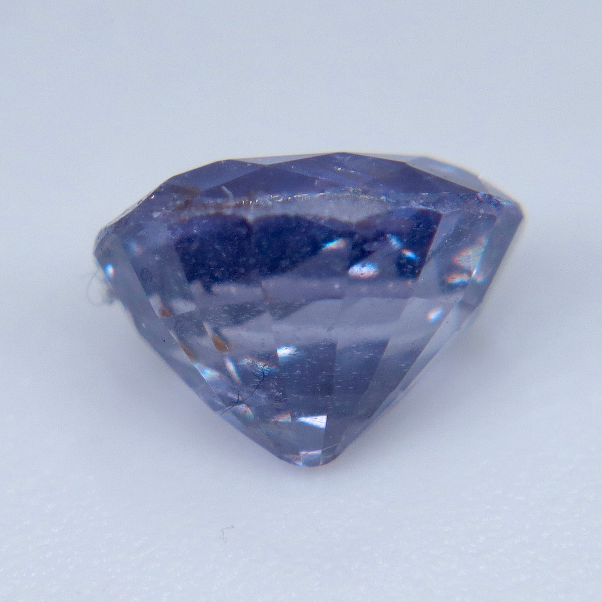 Underside view of an oval purple sapphire showing pavilion facets and inclusions