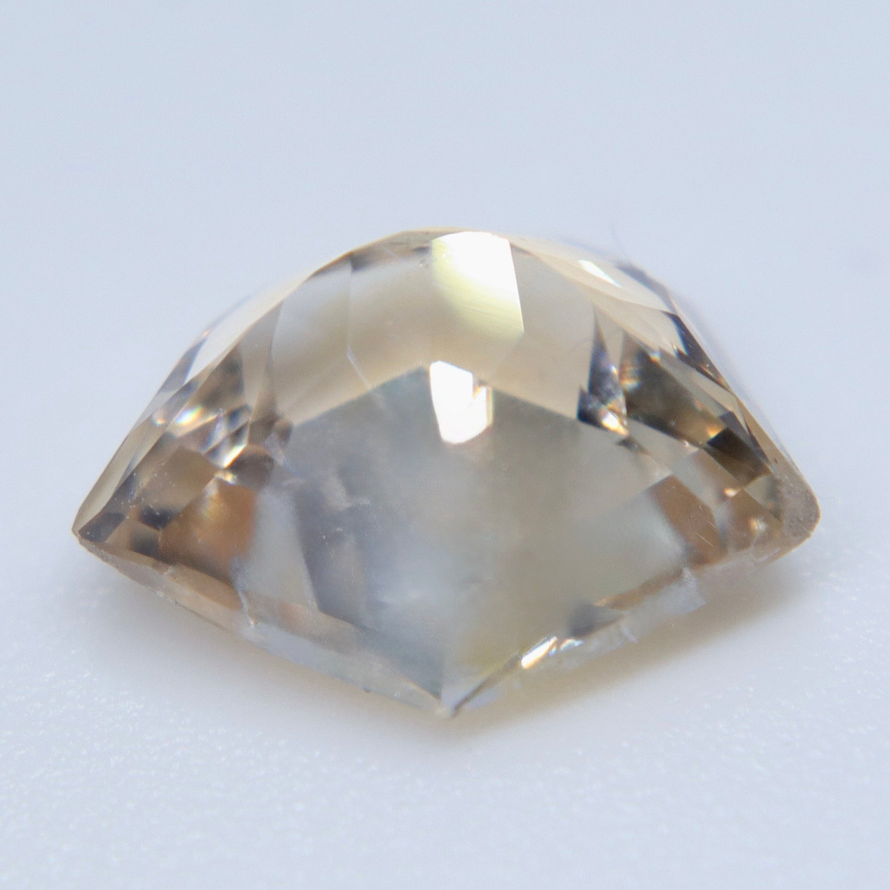 Pavilion view of the pale silver-champagne Ceylon sapphire showing its freeform cut and golden undertone