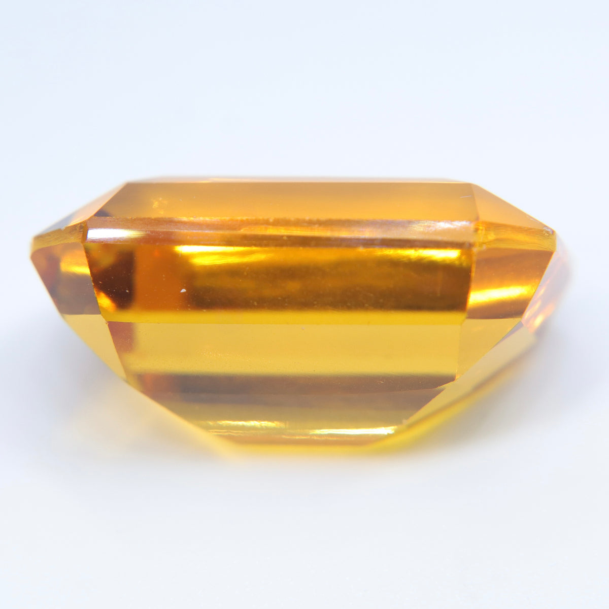 Side profile of a loose emerald-cut citrine showing its crown, girdle, and deep pavilion