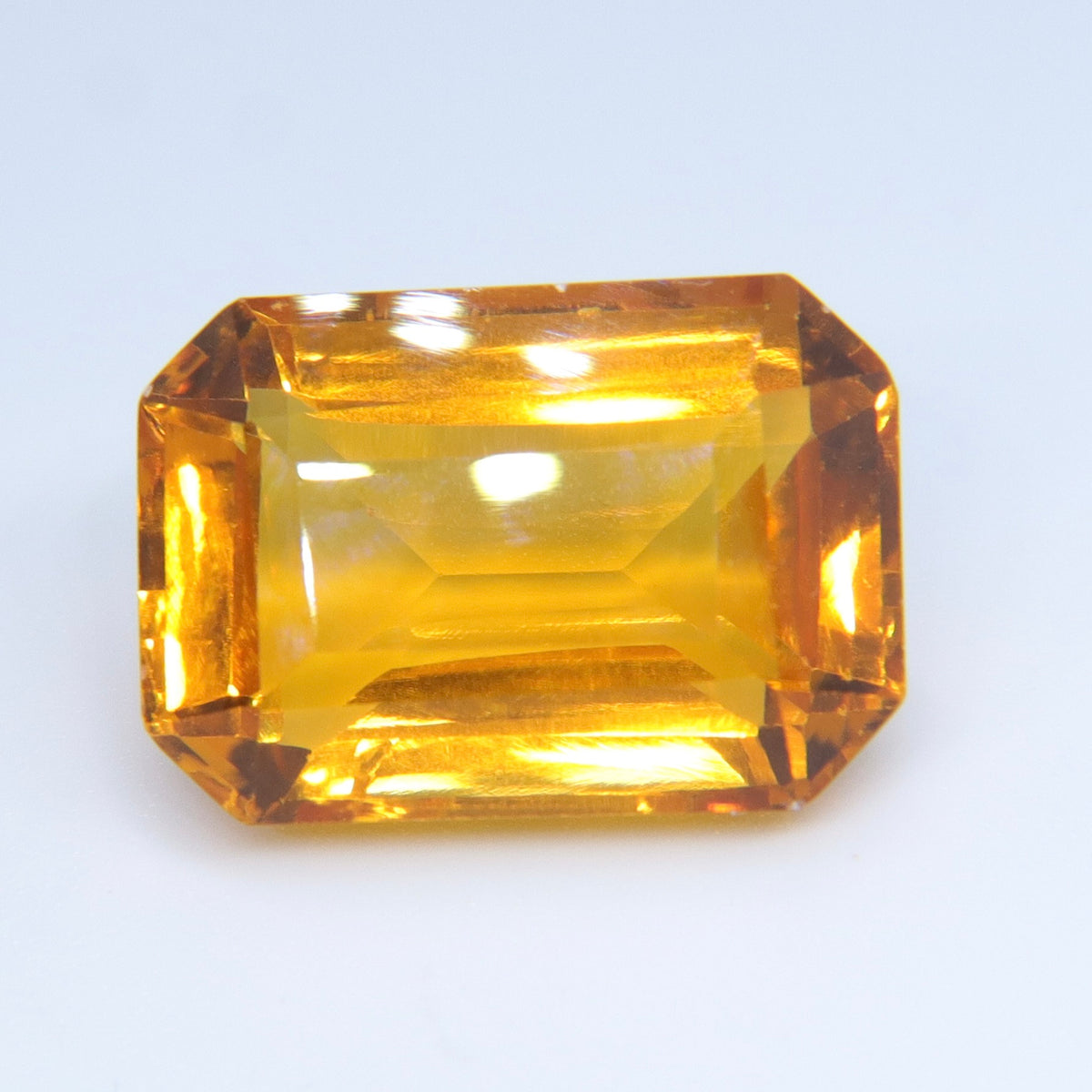 Golden emerald-cut citrine viewed at a slight angle, showing its step facets