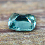 Angled view of a green cushion-cut sapphire showing its crown facets