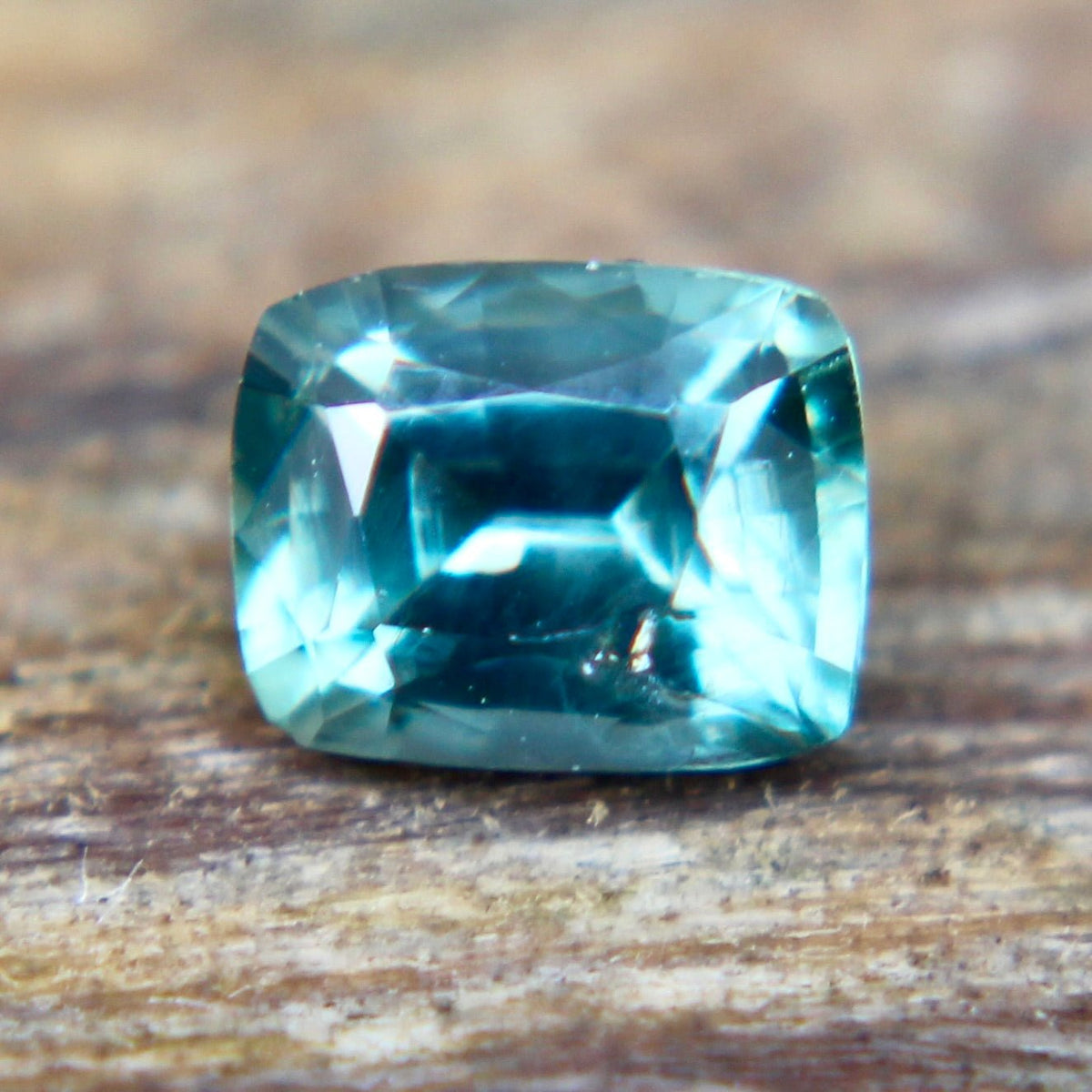 Underside view of a green cushion-cut sapphire showing its pavilion facets