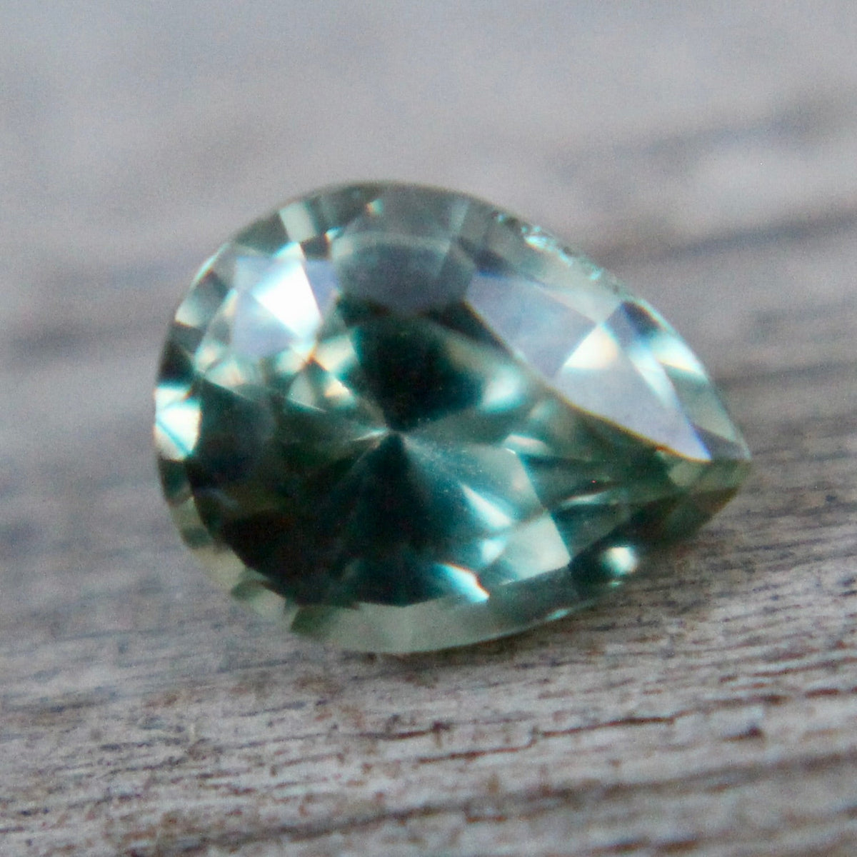 Angled view of a green sapphire showing its pear shape and crown facets