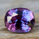 Loose 1.50 carat purple sapphire shown on hand for scale