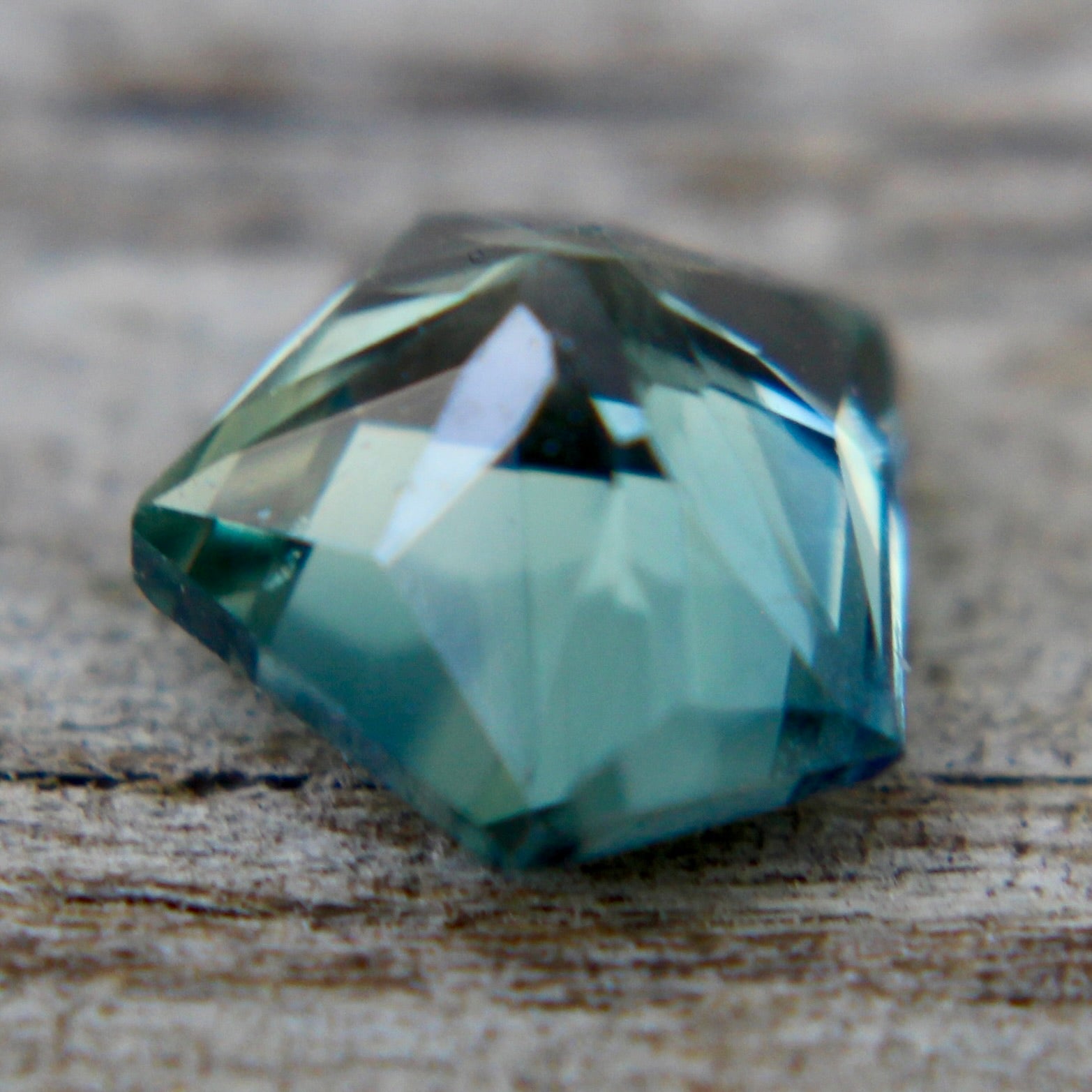 Close up of natural blue green sapphire with freeform cut and eye clean clarity