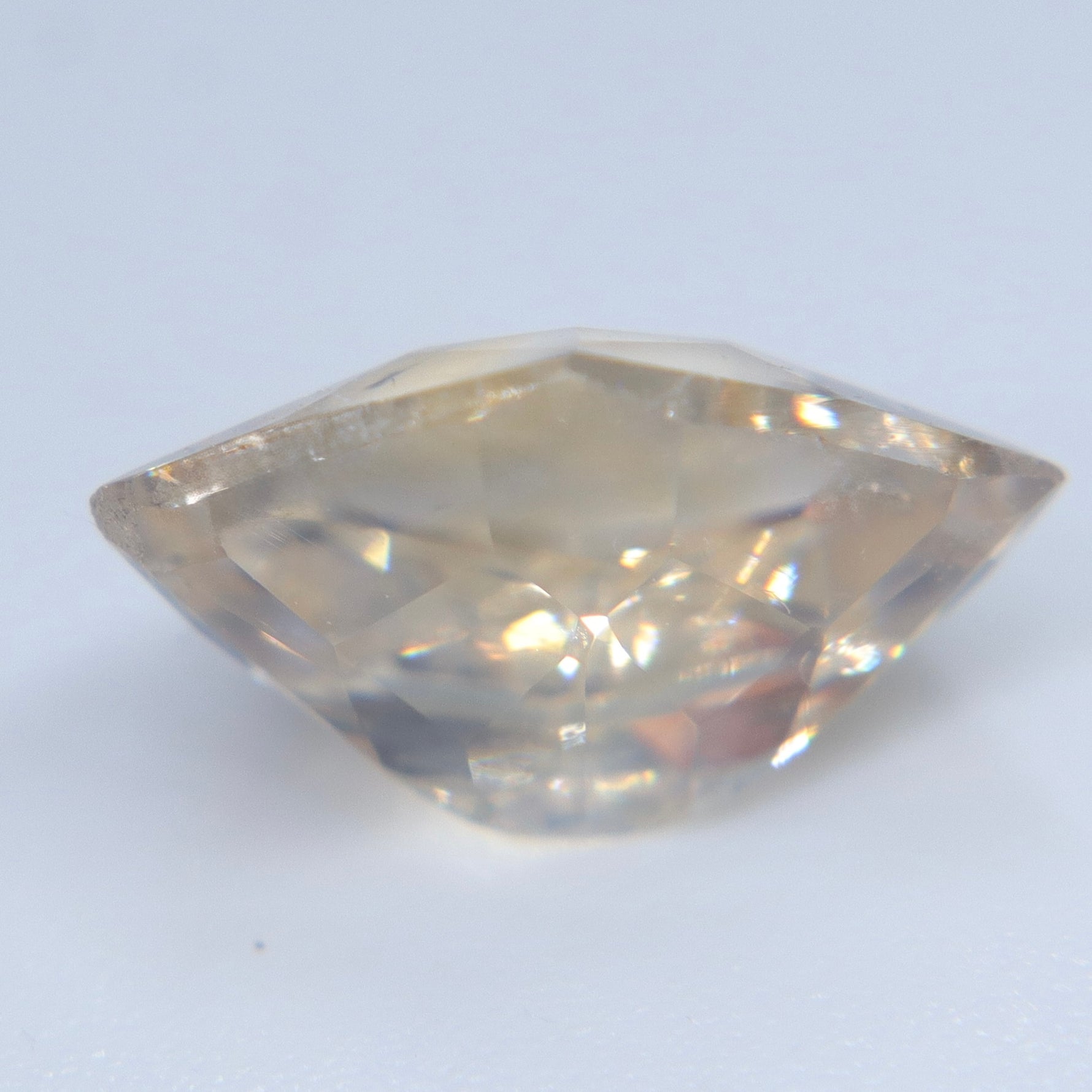 Angled view of the untreated Ceylon sapphire showing its asymmetric shape and pale champagne tone