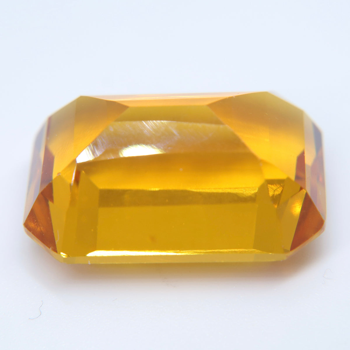 Tilted view of an emerald-cut citrine showing its golden color and pavilion facets
