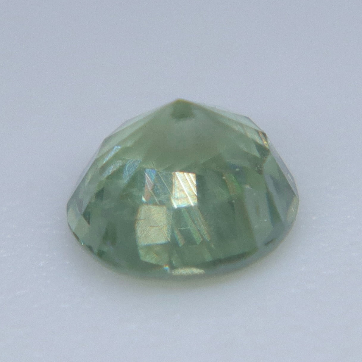 Side profile of a 0.34ct natural green sapphire showing its round faceting and 2.80 mm depth