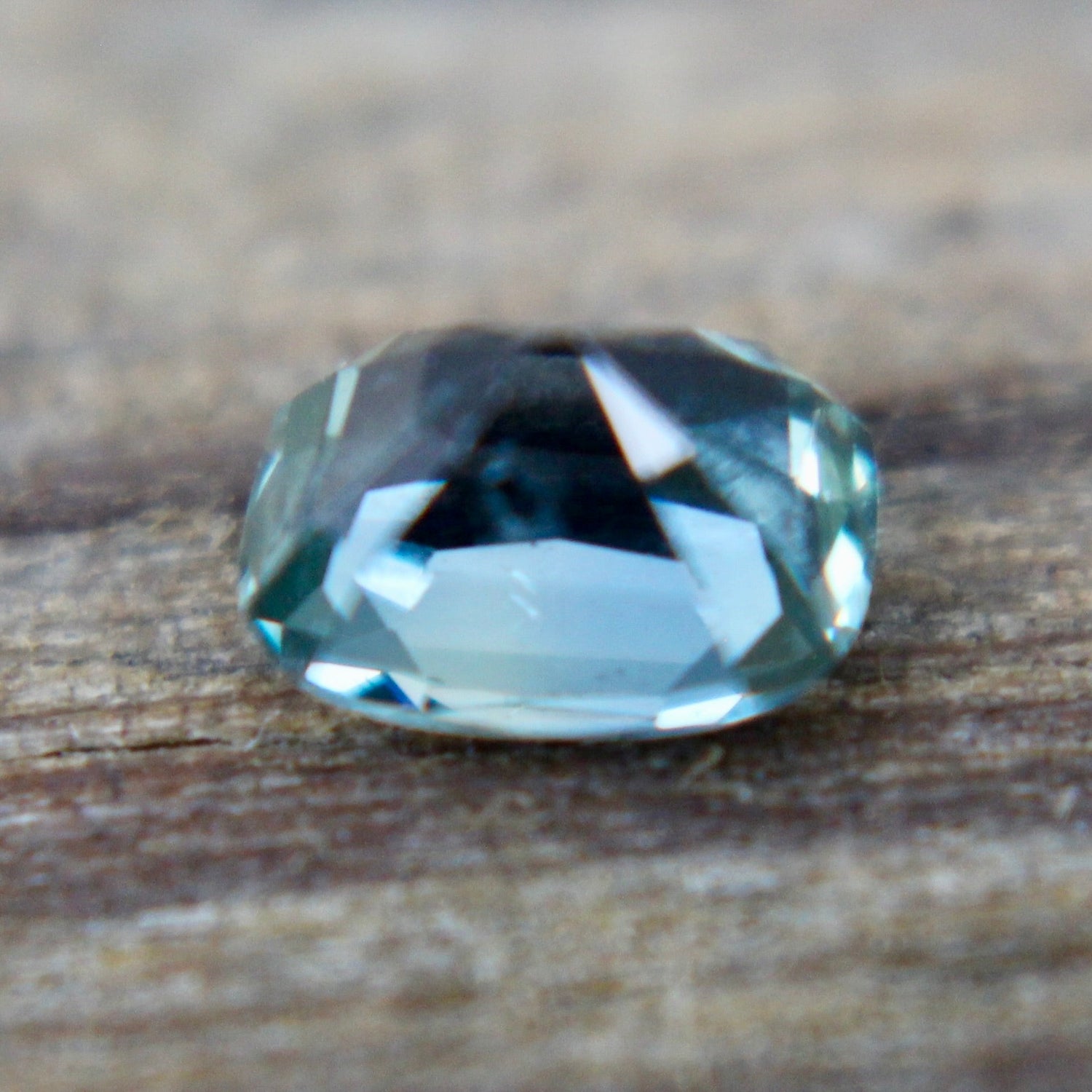 Cushion cut green sapphire 0.80 carat showing lively facets in neutral lighting