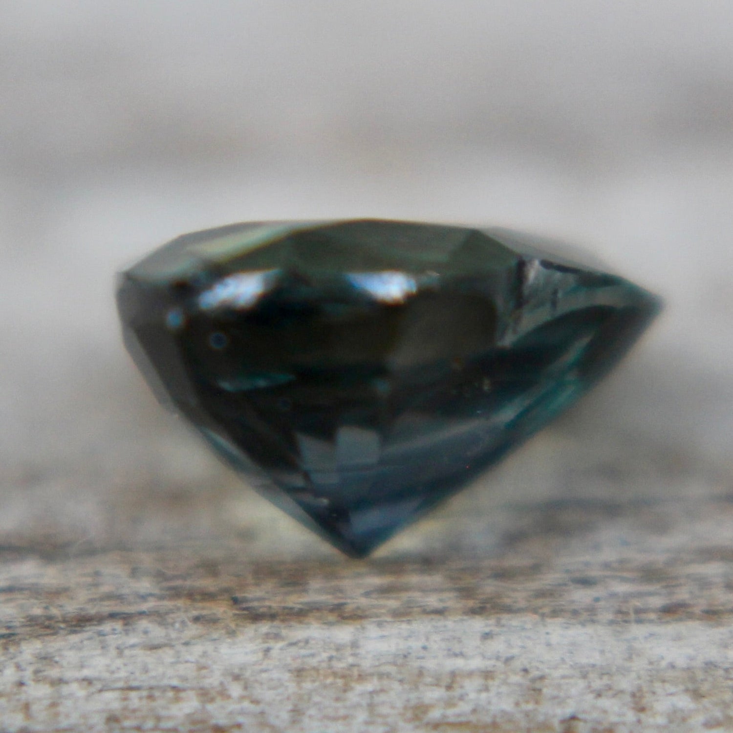 Earth sourced unheated green sapphire 6.63 x 5.60 x 3.50 mm shown in tweezers
