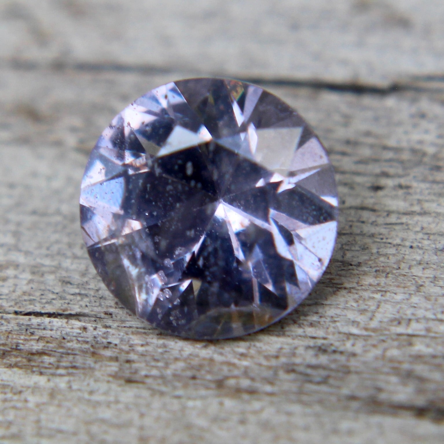 Back view showing natural inclusions in a round purple spinel