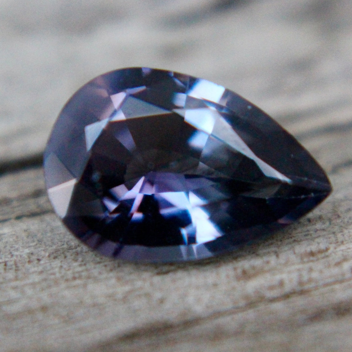 Angled view of natural purple spinel showing pear-cut facets and polish