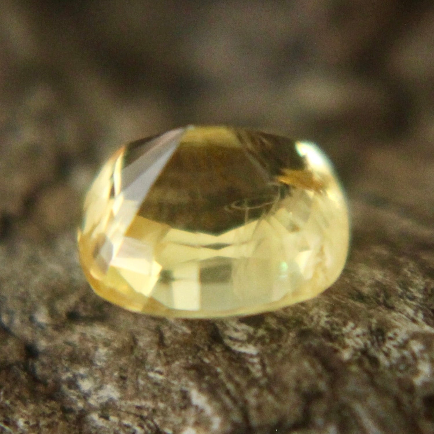 Cushion yellow sapphire showing bright facets in neutral lighting