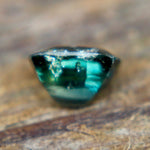 Angled view of a teal green cushion-cut sapphire showing its crown facets