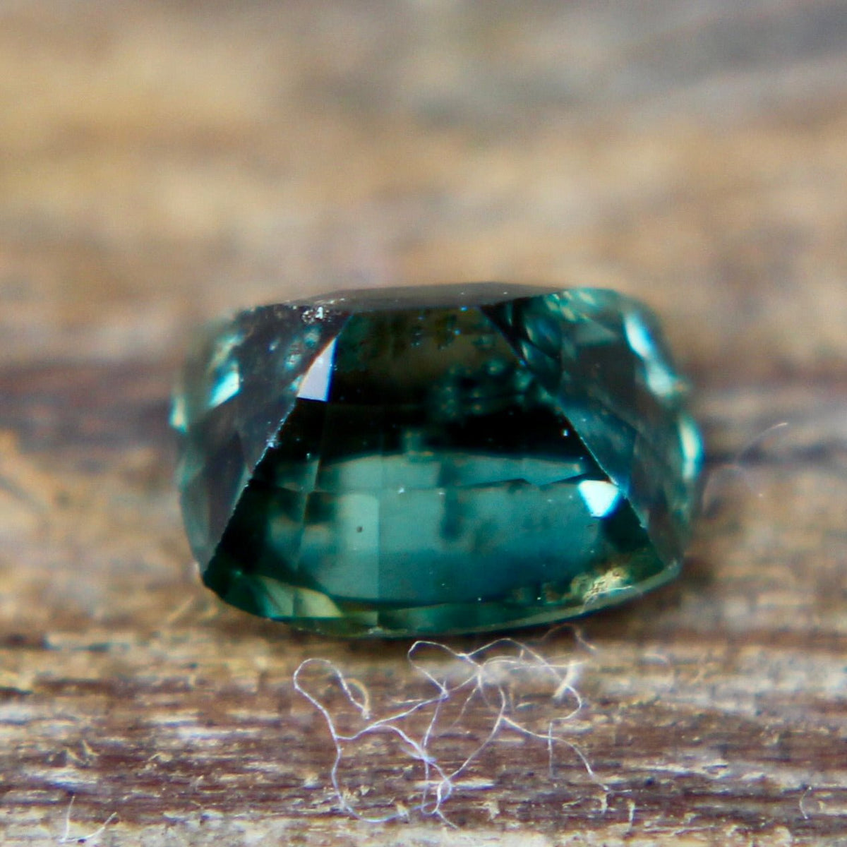 Close-up of the table and surrounding facets of a teal green sapphire